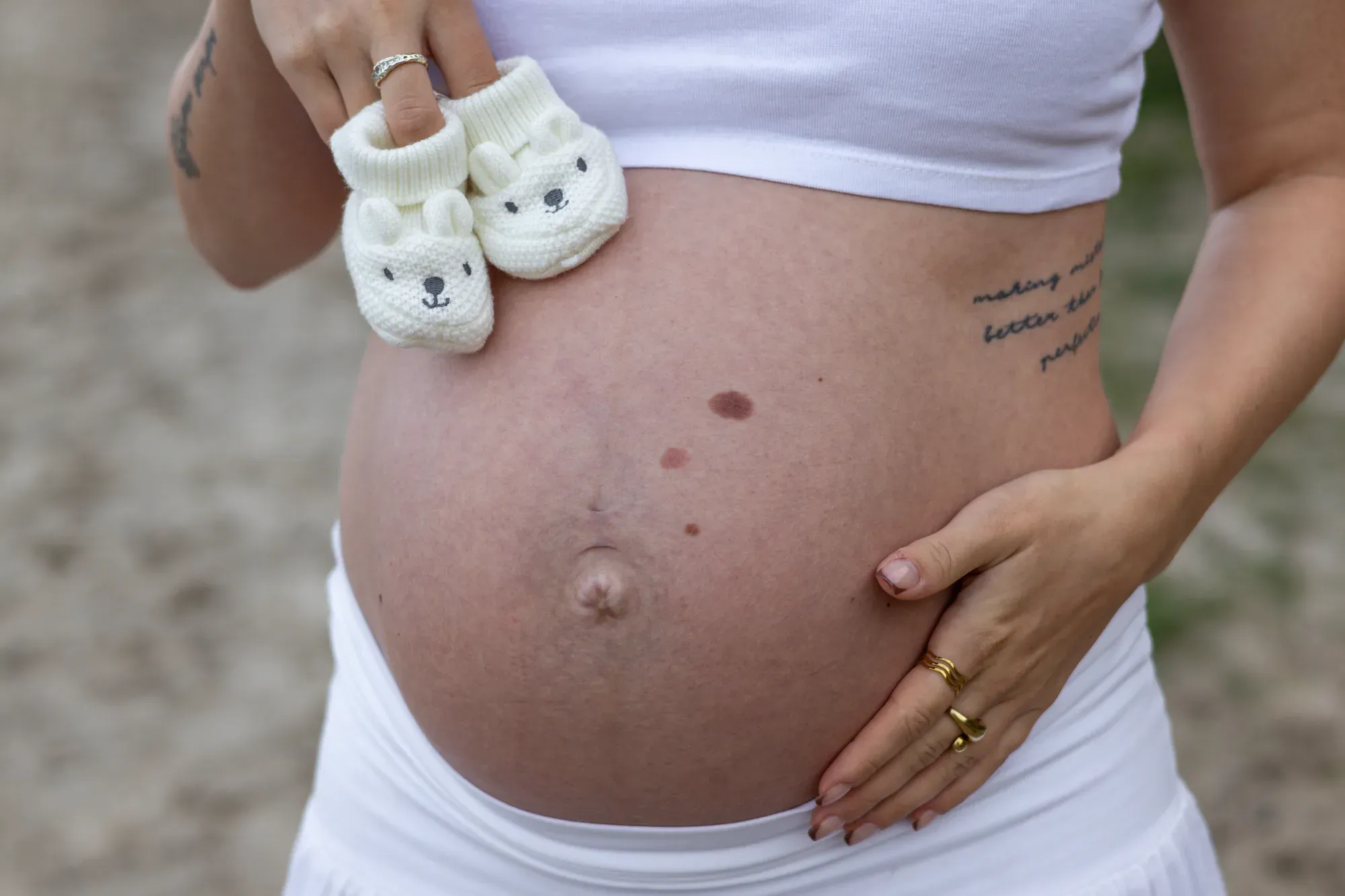 Detail: Kleine Babyschuhe auf dem nackten Babybauch