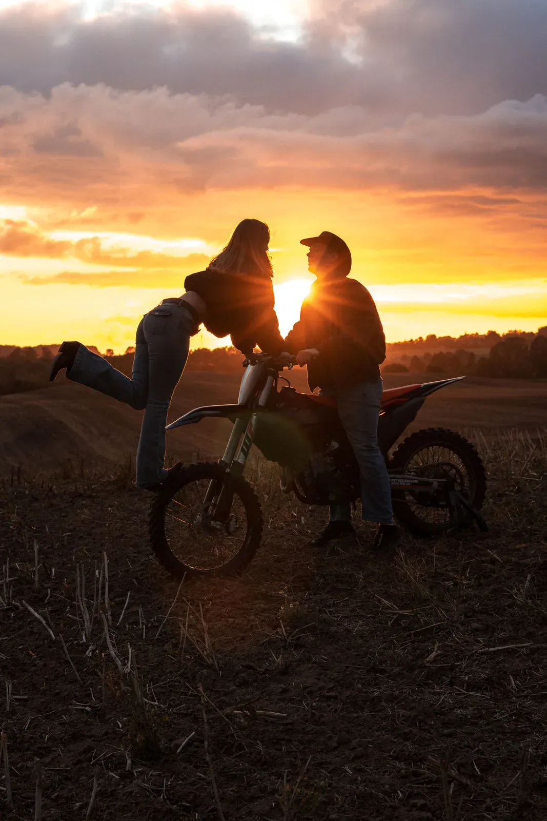 Silhouette eines Paares mit Motorrad vor dem Abendhimmel