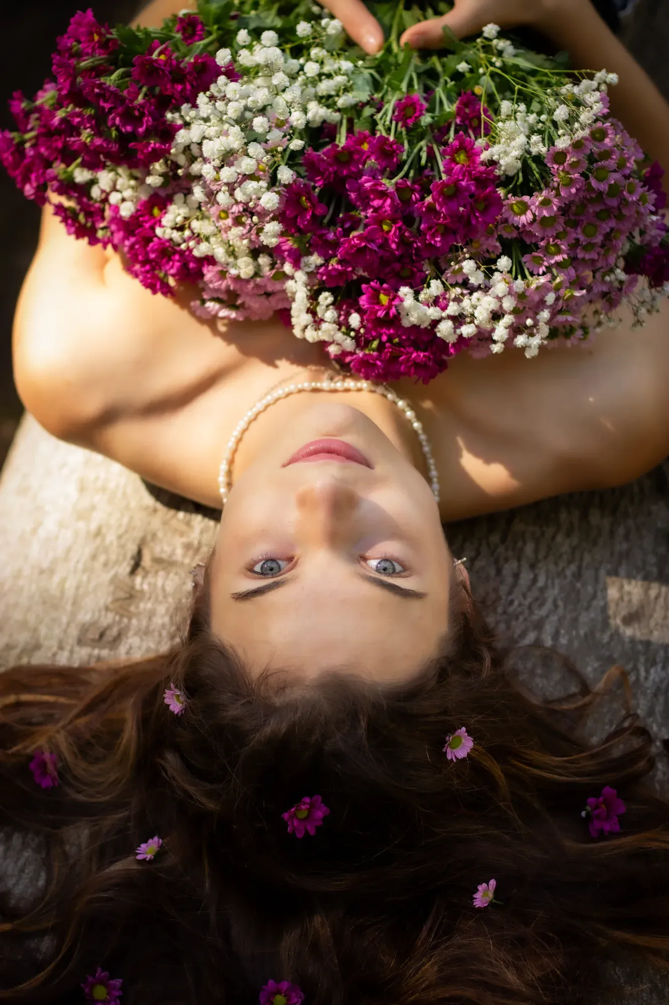 Frau liegt unter einem großen bunten Blumenstrauß, von oben fotografiert