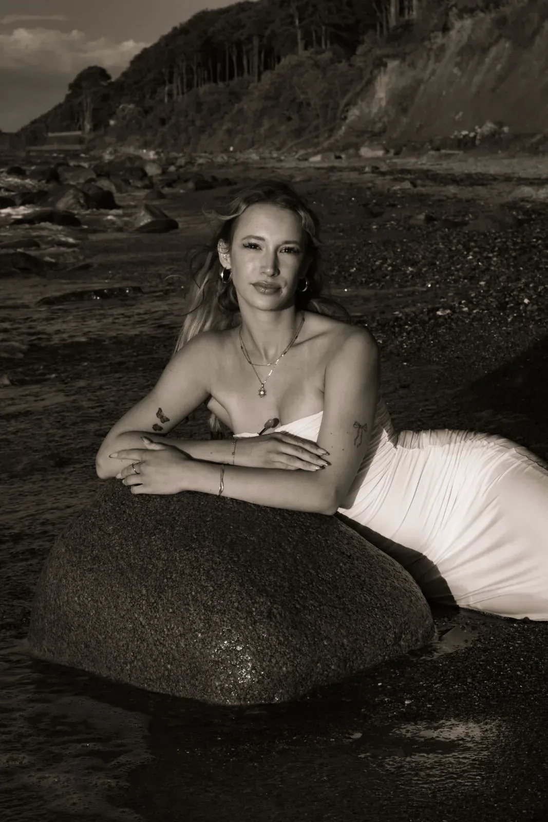 Schwarzweißbild: Frau liegt auf einem Stein am Strand