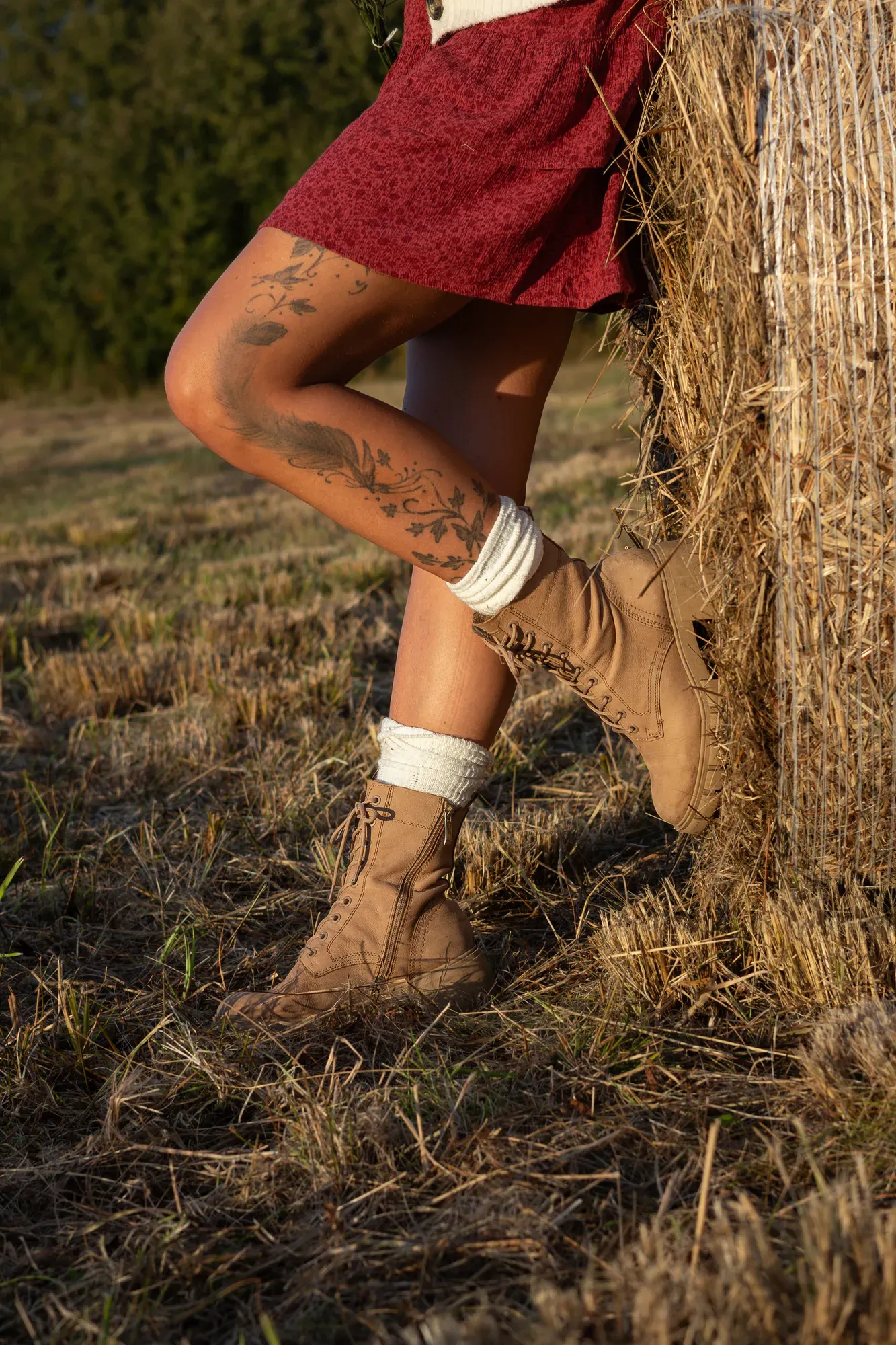 Detail: Tätowiertes Bein und Schnürstiefel vor einem Strohballen