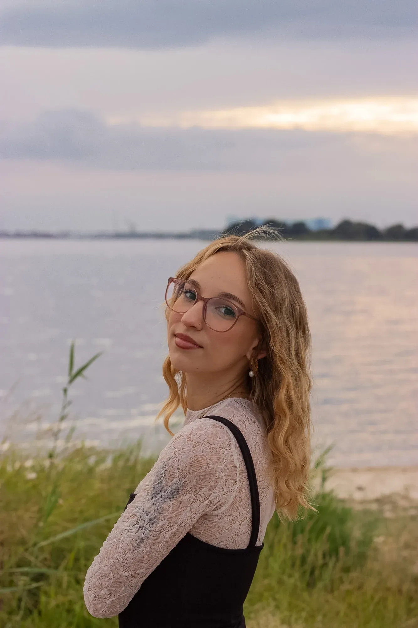 Frau mit Brille blickt am Ufer über die Schulter
